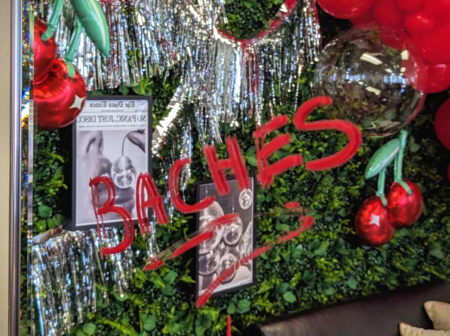 A mirror reflection of a Fete Events backdrop by Melissa Burgio of Fete Events and Bad Baches. Baches is written in red lipstick on the mirror, showcasing the playfulness of this girls night out event