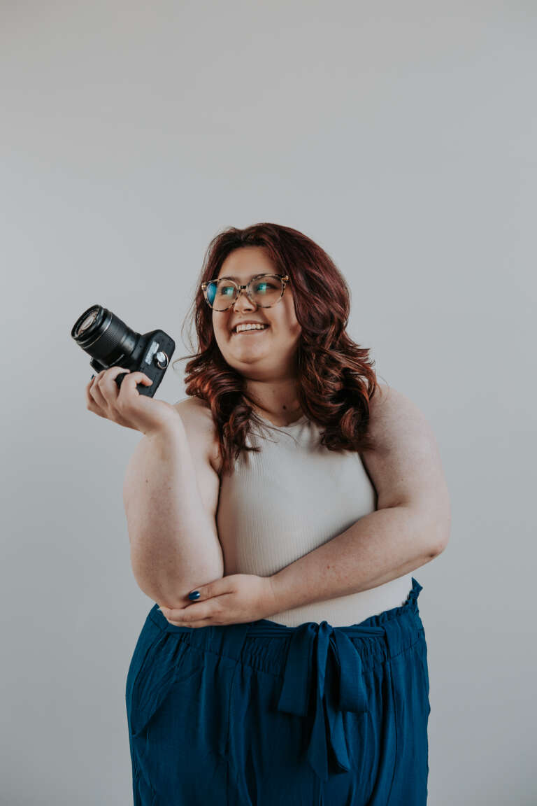Rebecca Nagel, owner of Kenmore Media, smiling while holding a camera